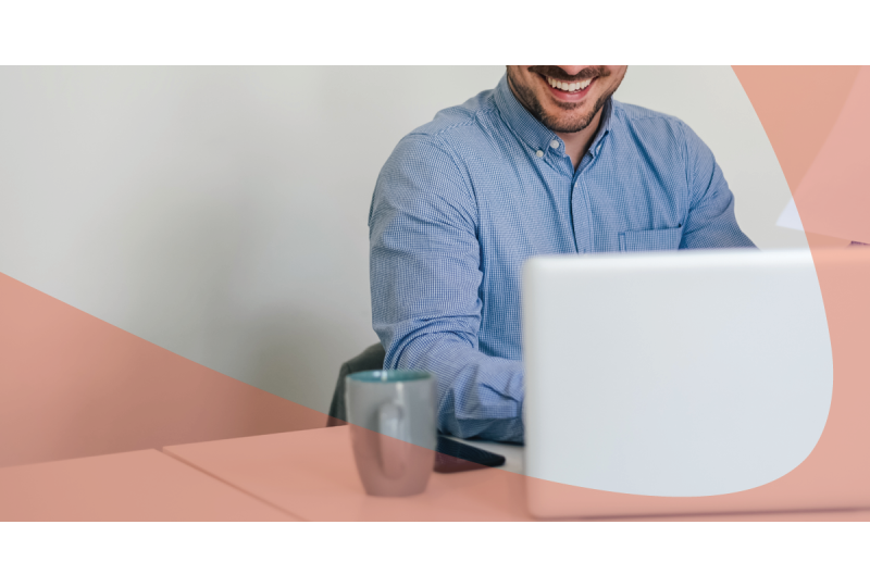 man working on work desk with laptop and a cup