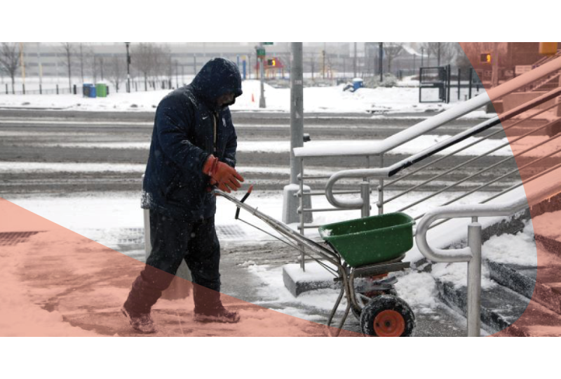 man applying ice melt on pavement in winter